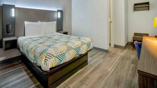 A hotel room with a bed, bedside tables, a nightstand, a desk, and a chair. - 1 Full Bed | ADA | Tub (Richland)