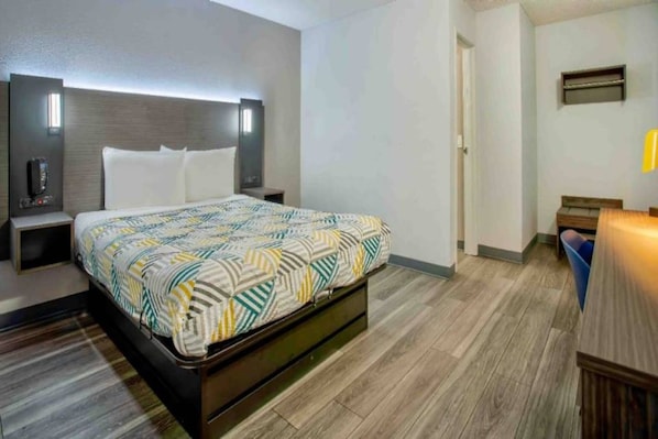 Een hotelkamer met een bed, nachtkastjes, een bureau en een stoel.