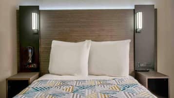 A hotel room with a bed, two bedside tables, and wall-mounted lamps.