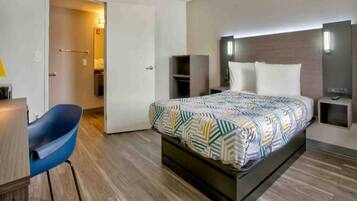 A hotel room with a bed, a desk, a chair, and a wardrobe.