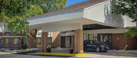 Un motel doté d’un parking couvert, d’une façade en briques et d’une voiture garée à l’intérieur.