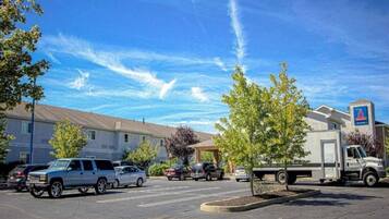 A parking lot with several vehicles, a building with a sign, and a clear sky.