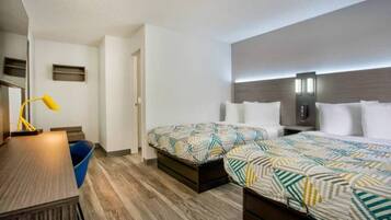 Een hotelkamer met twee bedden, een bureau, een stoel, een lamp en een kleine blauwe prullenbak.