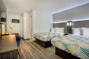 Une chambre d’hôtel avec deux lits, un bureau, une chaise, une lampe et une petite poubelle bleue.