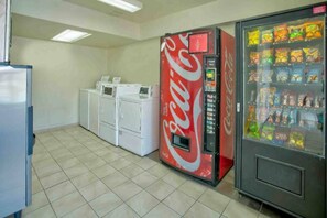 Une pièce équipée d’un distributeur automatique, d’un réfrigérateur et de plusieurs machines à laver empilées.