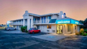 A motel with a 'Welcome' sign, a parking lot, and two cars parked in front. - 2 Full Beds | Micfridge (Richland)