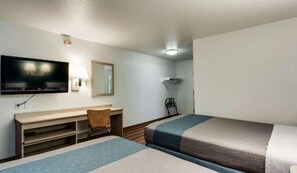 A hotel room with a bed, a desk, a chair, a television, and a mirror.