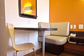 A corner seating area with a table and a chair, a wall-mounted light, and a telephone.