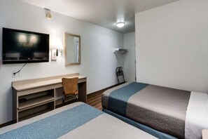Habitación de hotel con dos camas, un escritorio, una silla, un televisor y un espejo.