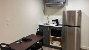 A compact kitchenette with a stainless steel refrigerator, a small sink, and a coffee maker.