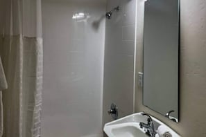 Een badkamer met een douche, wastafel en spiegel.