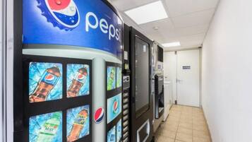 Zona de máquinas expendedoras con la marca Pepsi, piso de baldosas y una puerta al fondo.