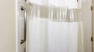 A bathroom with a white shower curtain, a grab bar, and a white door.