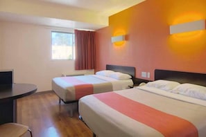Camera d'albergo con due letti, una scrivania e una finestra con tende.