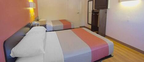 A hotel room with a bed, a television, and a small desk.