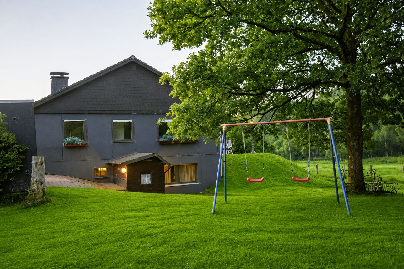 Une maison moderne avec une balançoire dans le jardin.