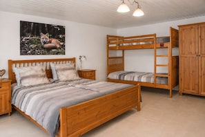 A bedroom with a wooden bunk bed, a single bed with a headboard, a nightstand, a lamp, and a wardrobe. - A cozy, well-furnished half-timbered house near Winterberg Hildfeld. (Hildfeld)