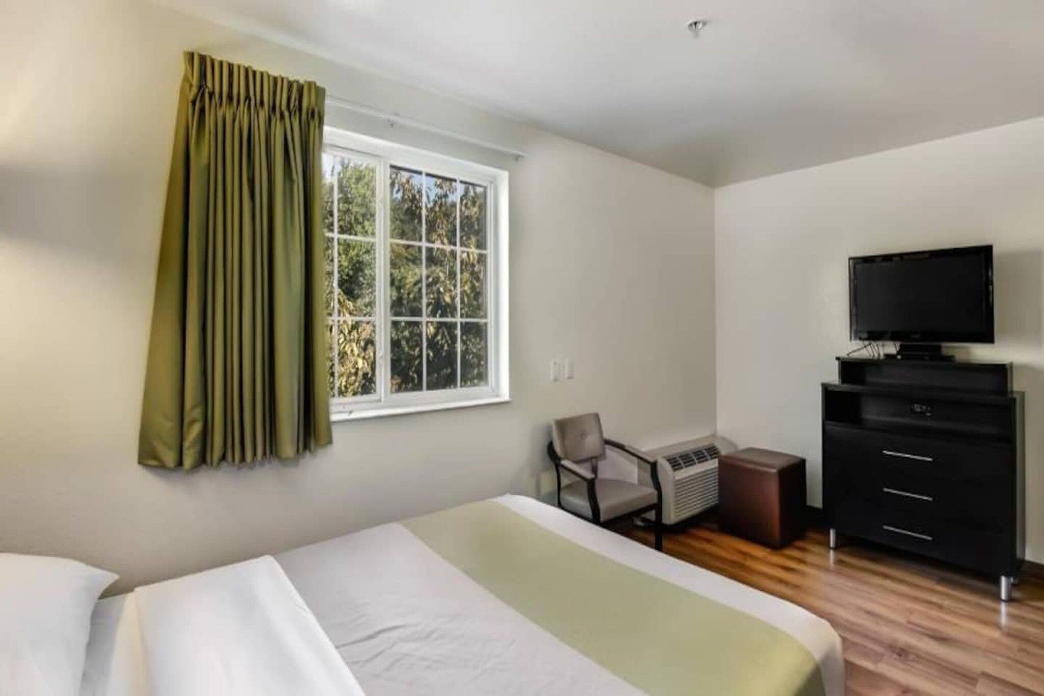 A hotel room with a bed, a television, a desk, and a chair.