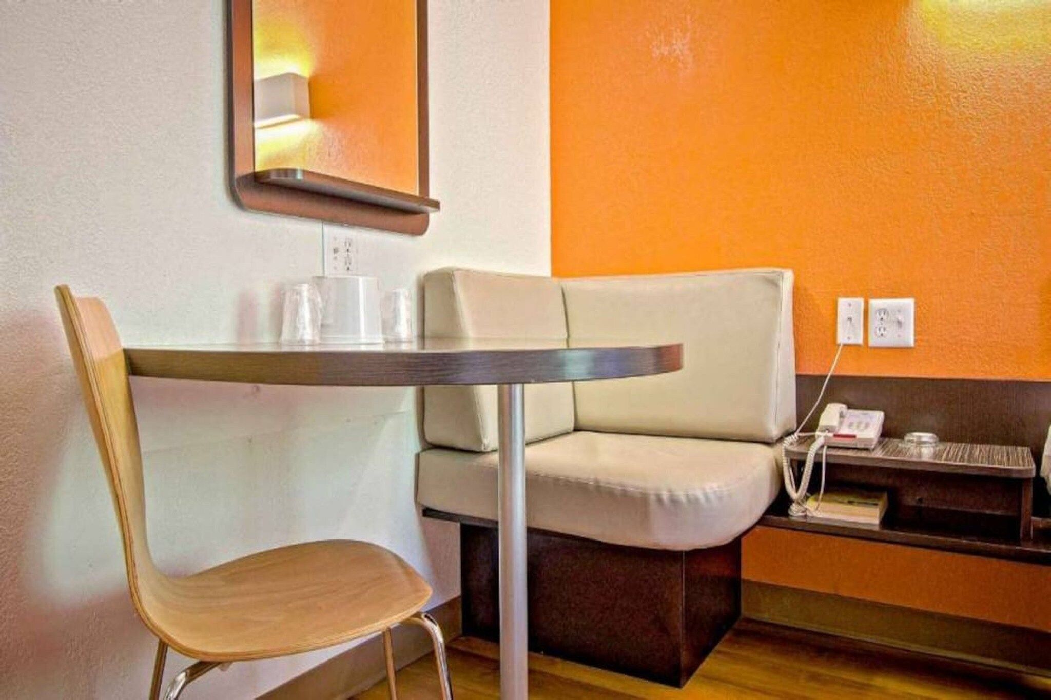 Una habitación pequeña con una mesa, una silla, un sofá y un teléfono.