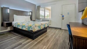 A hotel room with a bed, a desk, a chair, a window, and a door. - 1 Queen bed | Richland (Richland)