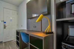A room with a desk, a chair, a lamp, and a door.