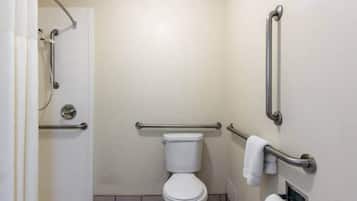A bathroom with a toilet, grab bars, a shower area, and a towel rack.