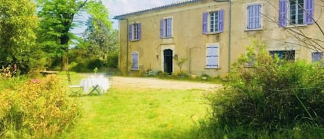 Una casa de dos pisos con puerta principal, un pequeño porche y un patio cubierto de césped.