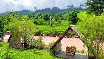A rural setting with traditional huts, a river, and lush greenery.