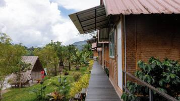 A wooden building with a covered walkway, surrounded by lush greenery and a clear sky.