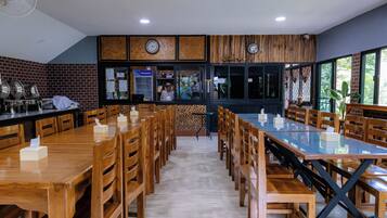 Un restaurante con mesas y sillas de madera, una pared de ladrillo y una barra con refrigerador.