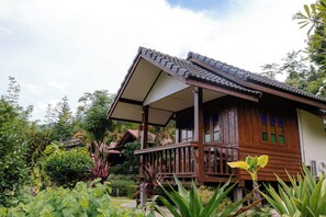 A wooden house with a porch, surrounded by lush greenery. - Saiwaree Farmstay (Bo Kluea)