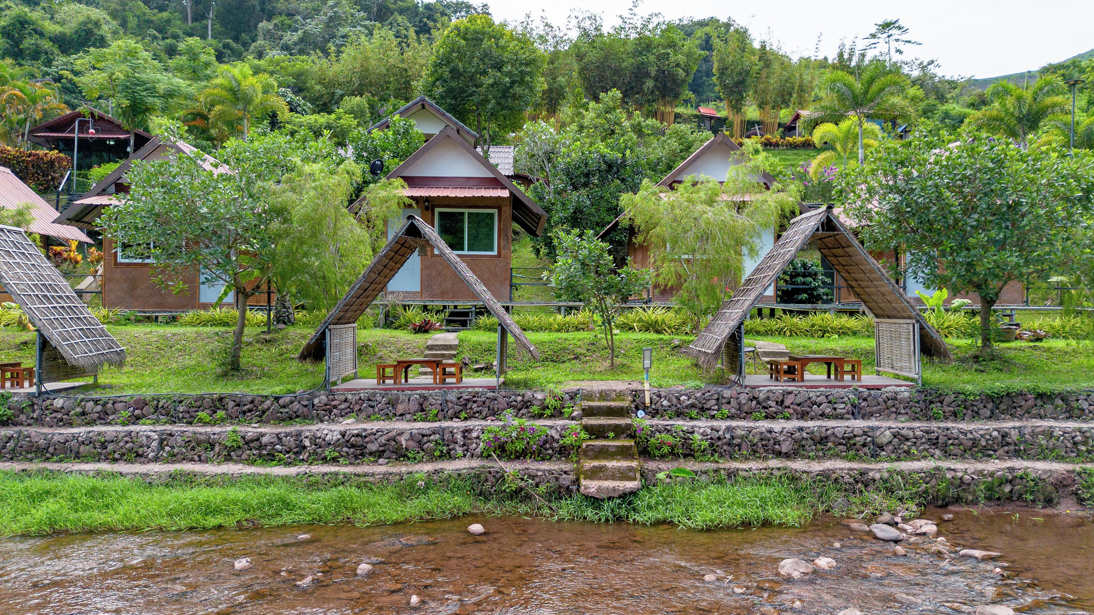 A series of traditional-style buildings with thatched roofs, arranged around a central water feature.
