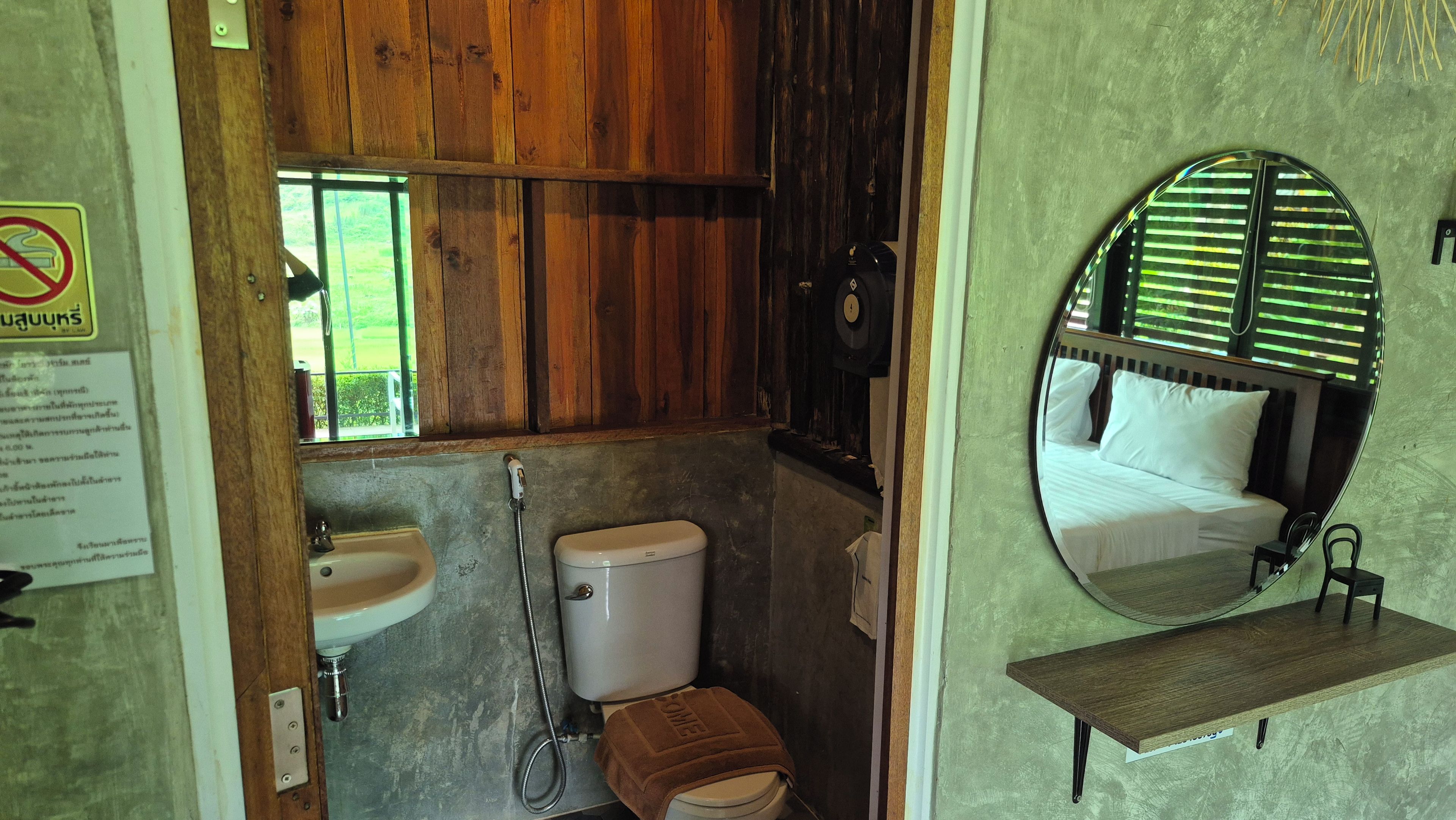 A bathroom with a toilet, sink, and a mirror above the bed.