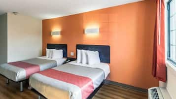 Een hotelkamer met twee bedden, een raam met gordijnen en een wandradiator.