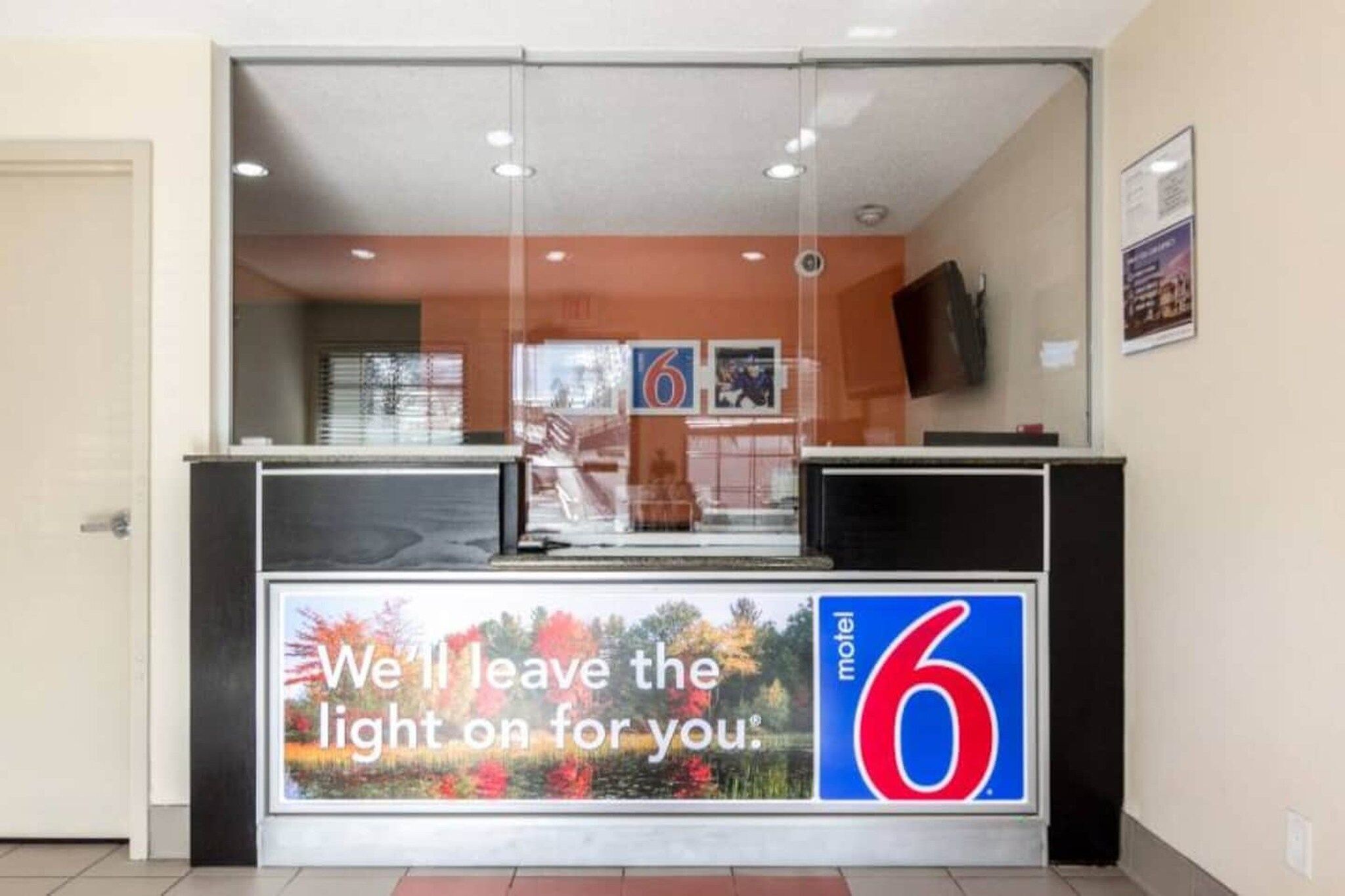 A motel reception desk with a large number '6' sign and a promotional message.
