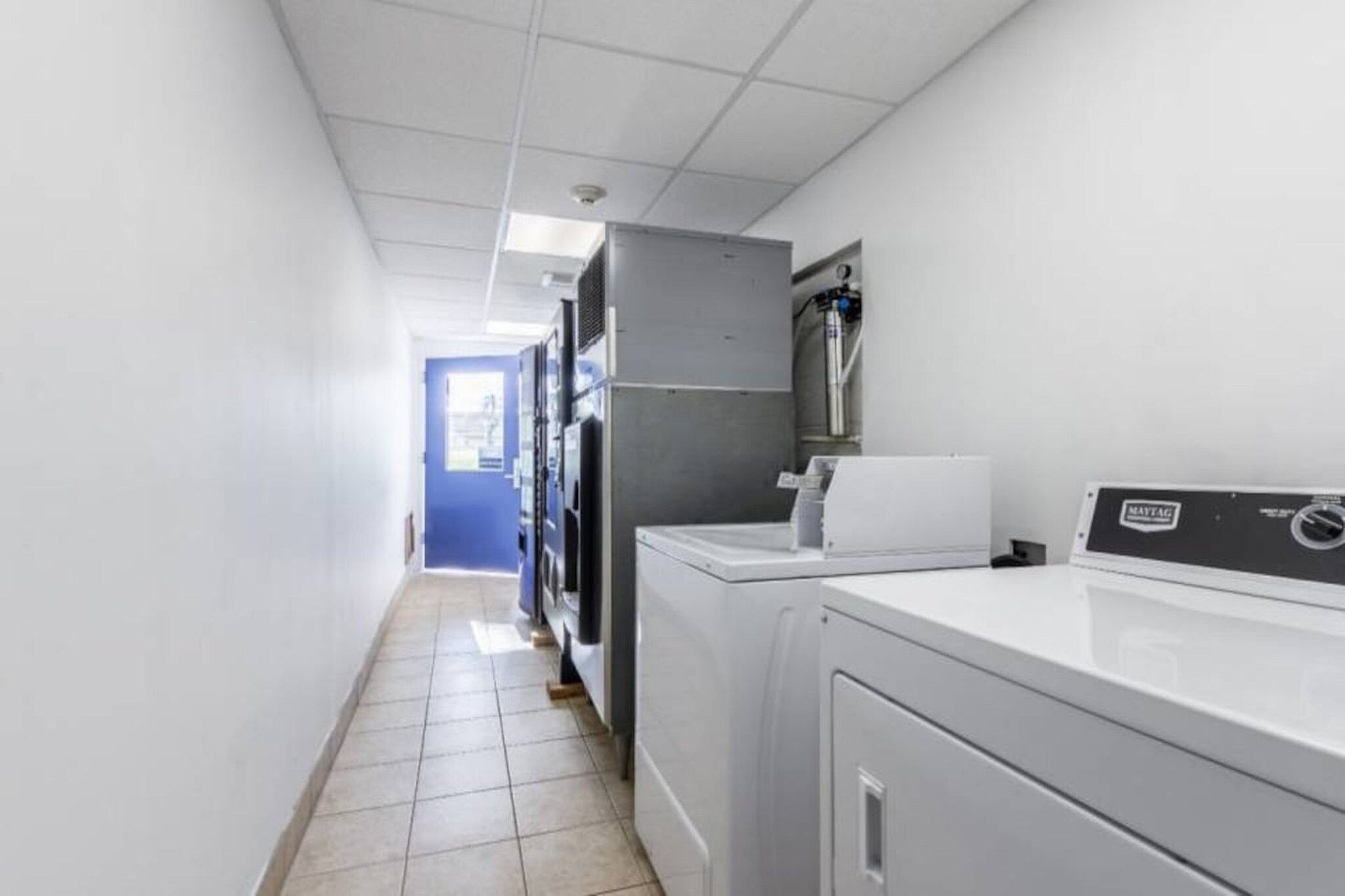 A laundry room with a washing machine, dryer, and stacked dryers in the background.