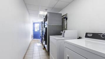 A laundry room with a washing machine, dryer, and stacked dryers in the background.