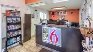 A reception desk with a large number '6' sign, a computer, and a counter with various items.