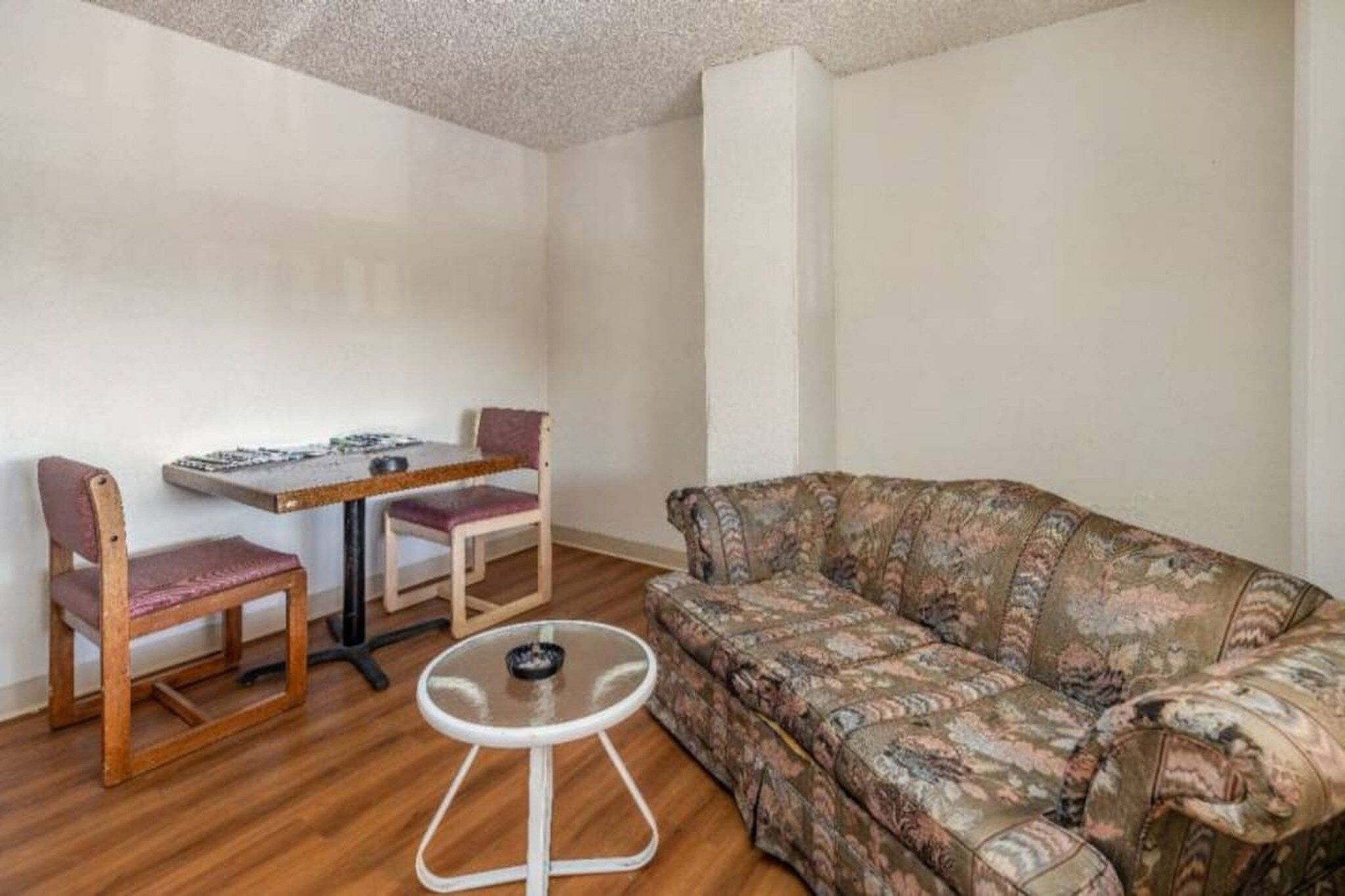 Et lille opholdsområde med en sofa, et spisebord med stole og et rundt bord.