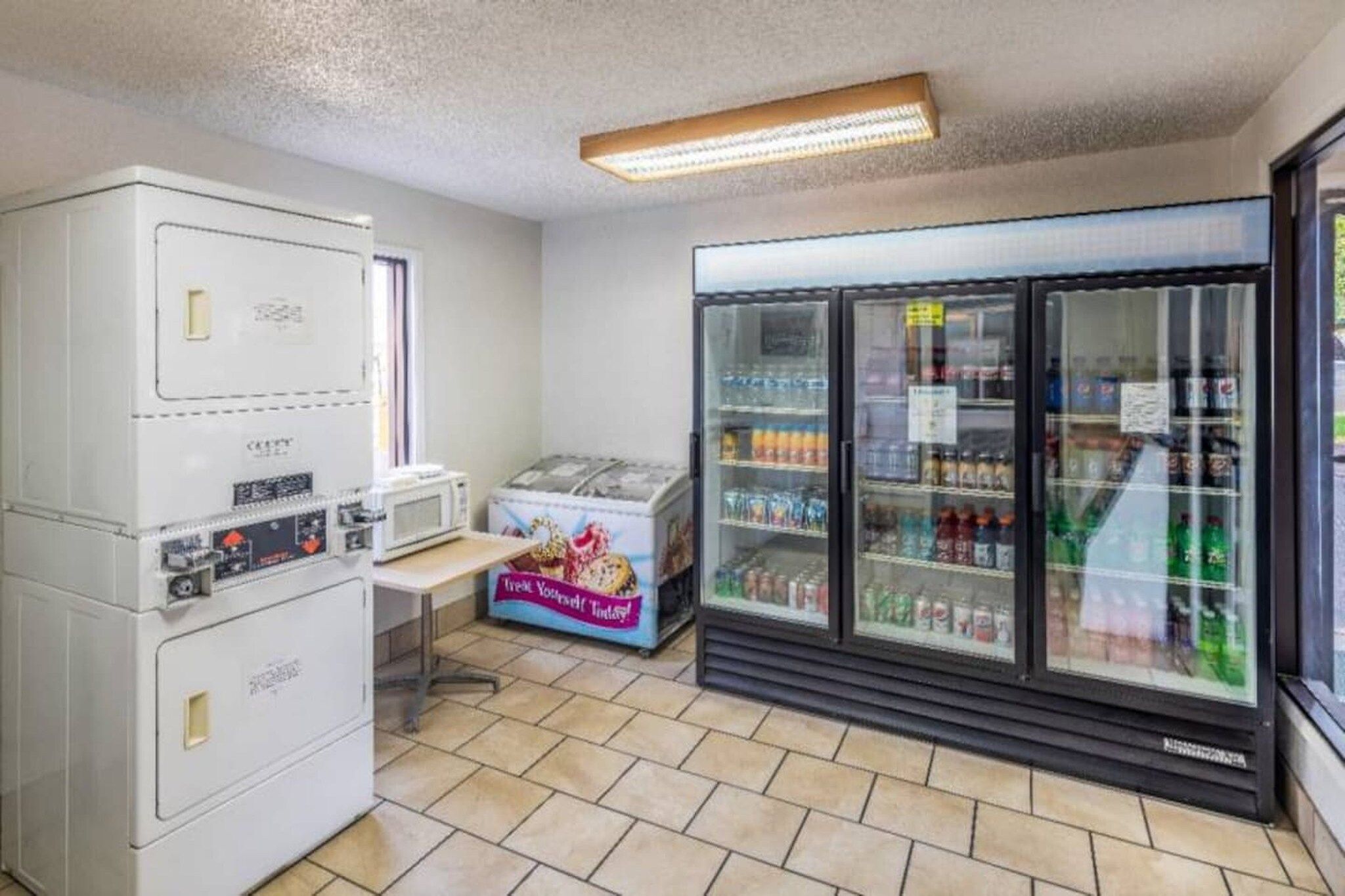 A small kitchenette with a microwave, refrigerator, and a vending machine.