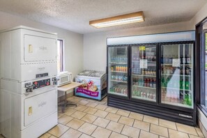 Una pequeña cocina americana con microondas, refrigerador y máquina expendedora.