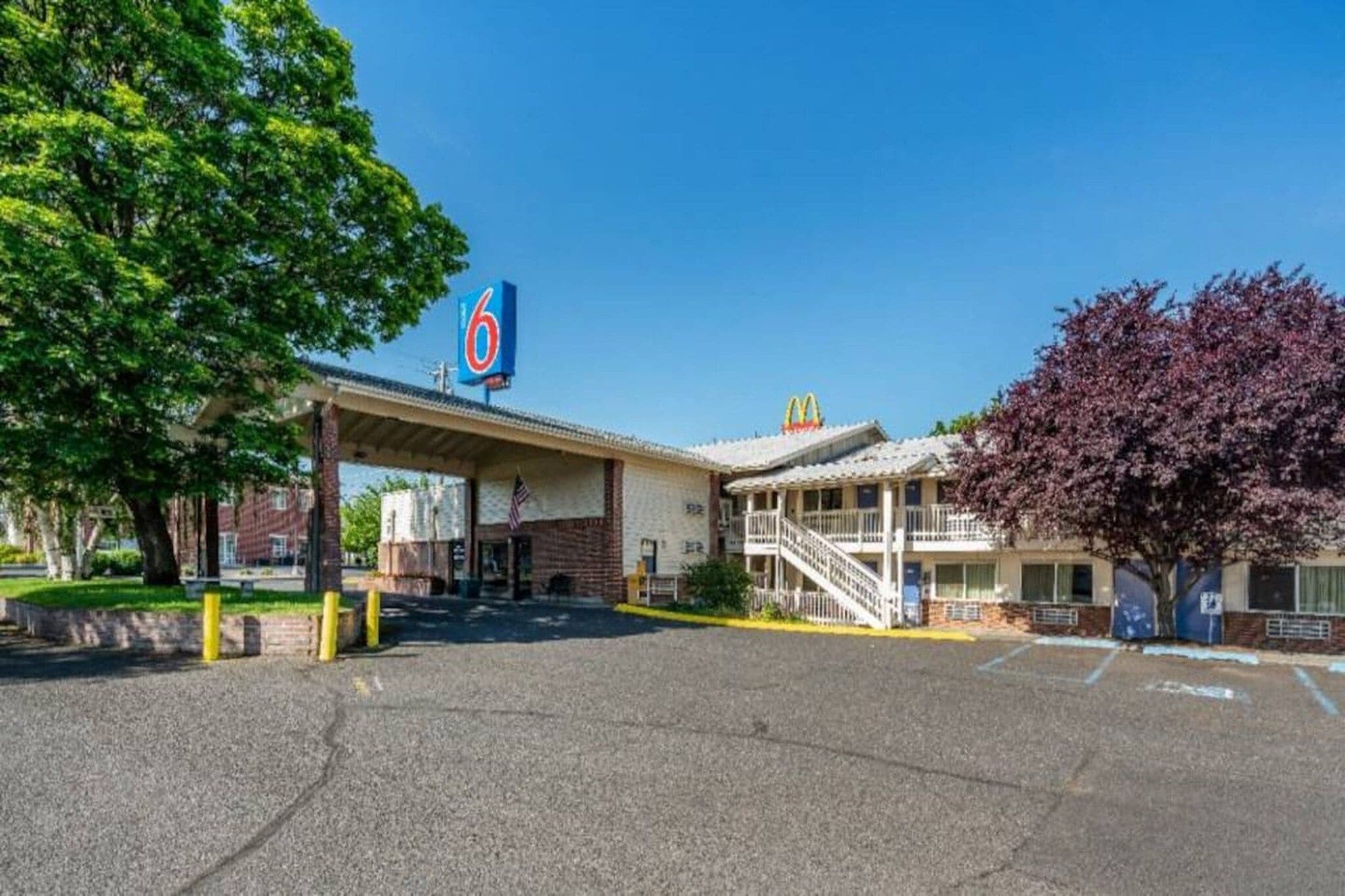 Un motel con un letrero de McDonald's, una zona de estacionamiento techada y un edificio con una escalera.