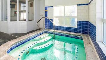 Une piscine bordée de carreaux bleus, avec une échelle en métal et une fenêtre au-dessus de la piscine.