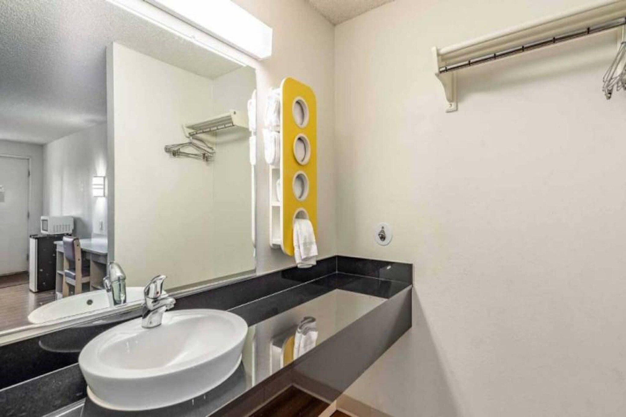 A modern bathroom with a large mirror, two sinks, and a towel rack.