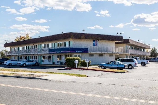 A motel with a two-story structure, a parking lot, and a clear sky.