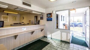 A reception area with a counter, a clock, and a door leading outside. - 1 Queen Bed | Mob Acc RI Shwr Nsmk Micfridg (Moses Lake)