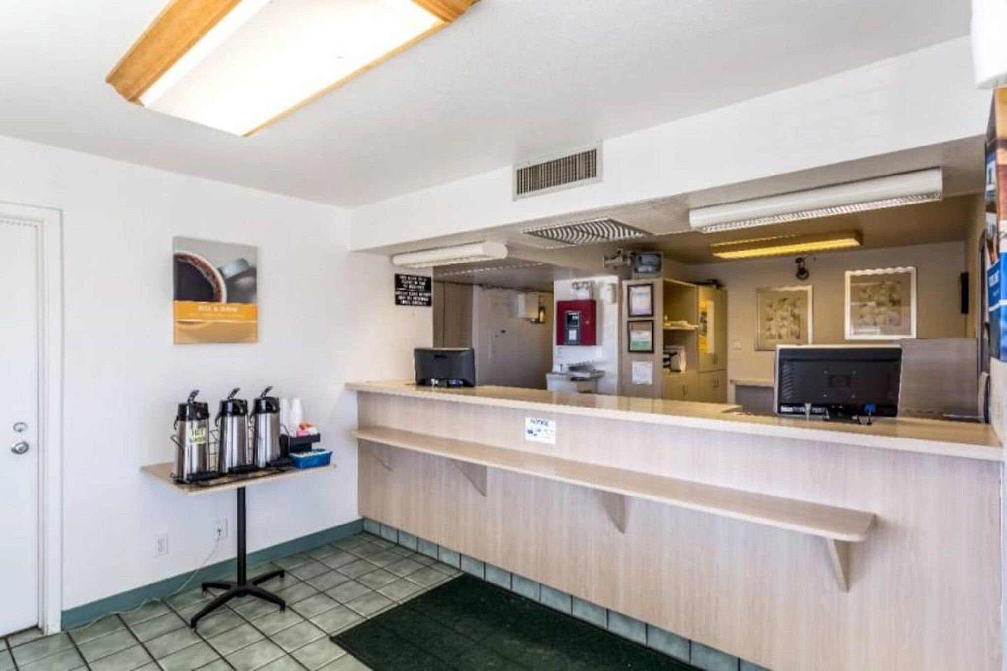 A reception desk with a computer, a coffee machine, and a sign indicating a smoking area.