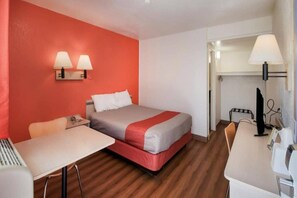 Ein Hotelzimmer mit einem Bett, einem Schreibtisch, einem Stuhl und einer Lampe.