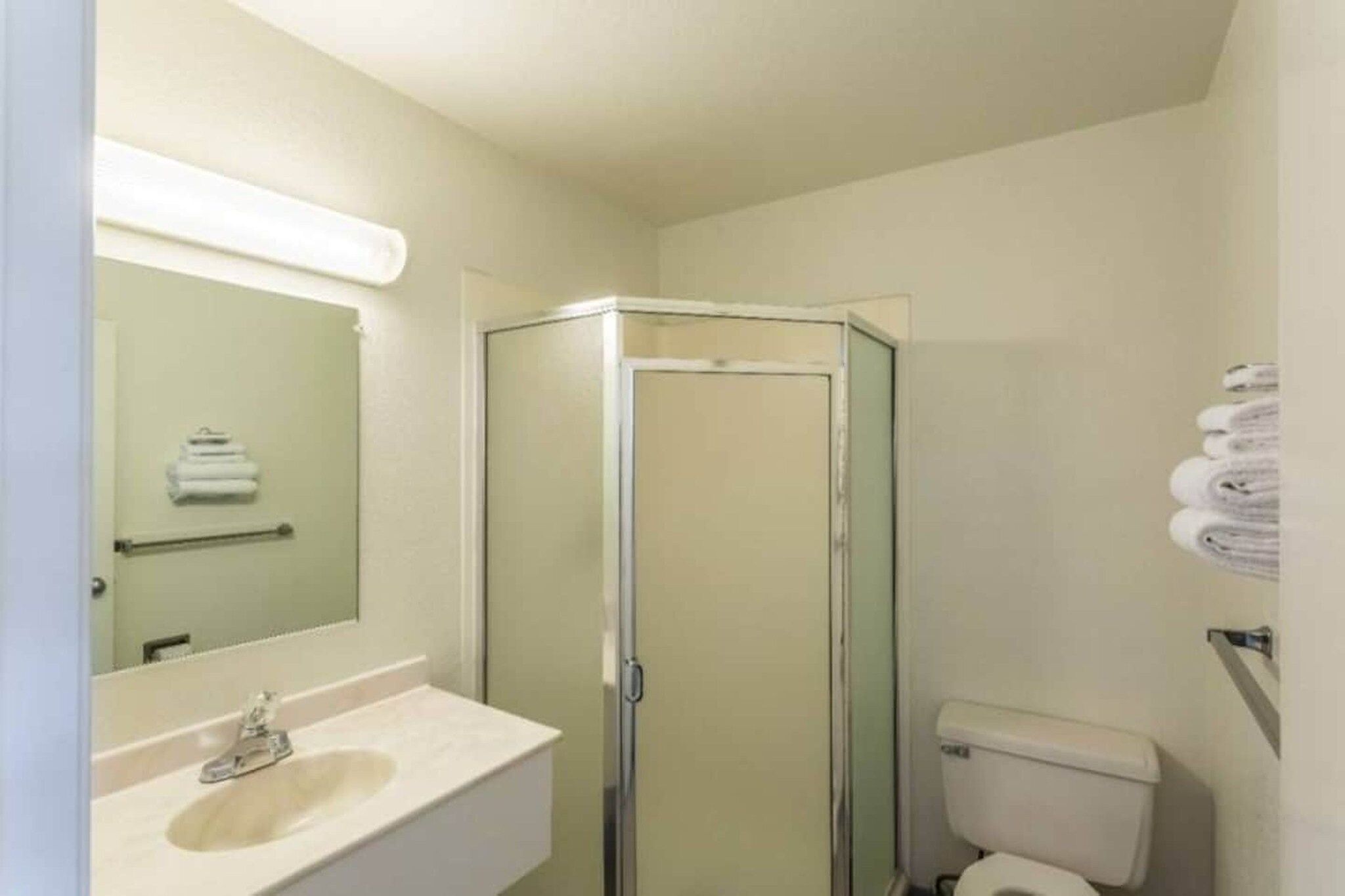 A bathroom with a glass-enclosed shower, a sink, and a toilet.