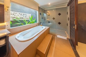 Ein modernes Badezimmer mit freistehender Badewanne, einer Glasdusche und einem Fenster mit Blick ins Grüne.